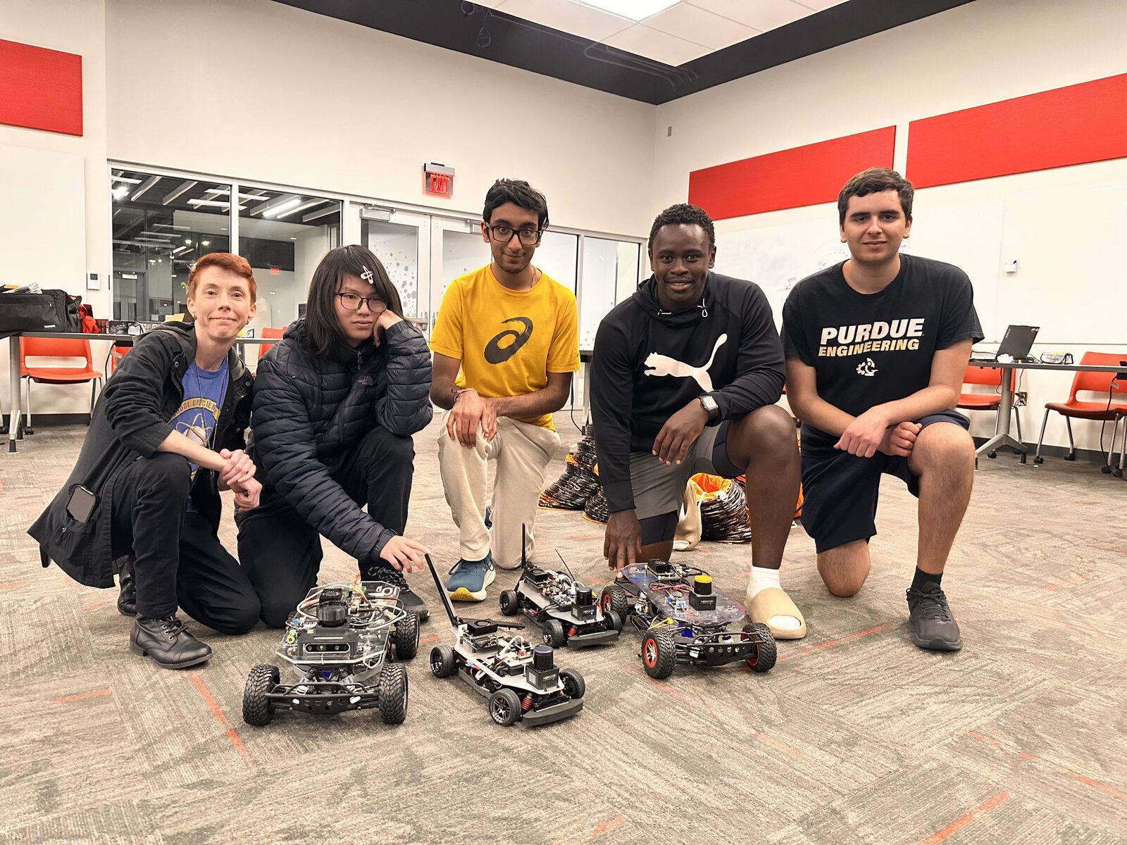 Members kneeling with four autonomous cars during a campus test night